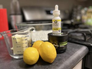 Stick of butter, lemons, Big Petes: Cannabutter, and Kitchen Gourmet: Lemon all on display on a kitchen counter next to a stove.